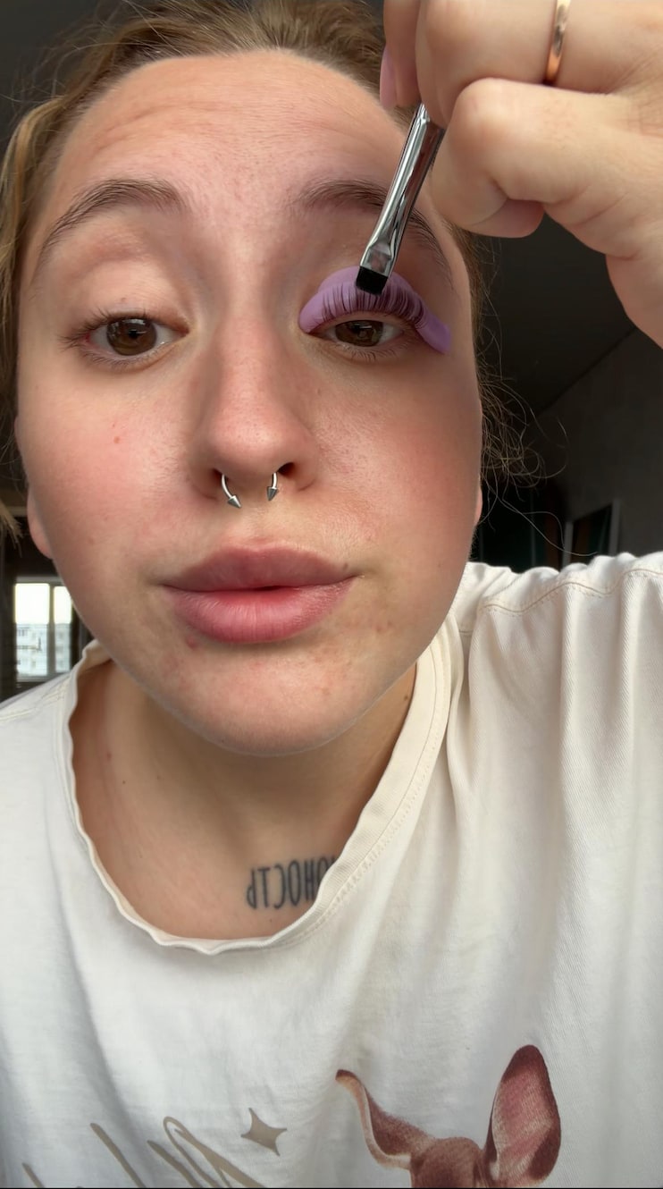 Натали сама наносит состав кистью на ресницы, закреплённые на лиловом валике
